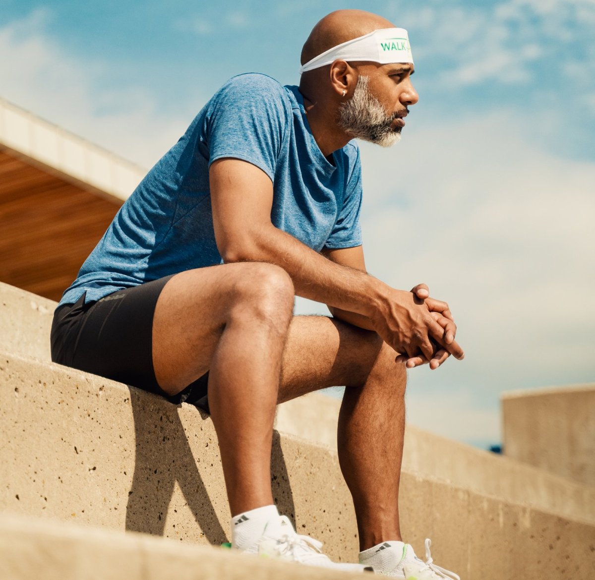 Man sitting on steps in athletic wear, reflecting and promoting the importance of physical activity and mental wellness, aligning with work-life balance themes.