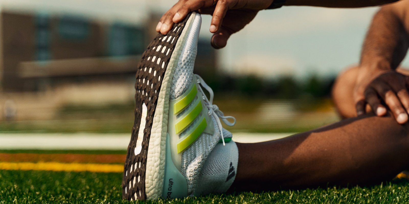 Person stretching in athletic shoes on a grassy field, emphasizing the importance of physical readiness and mindset for personal growth and success.