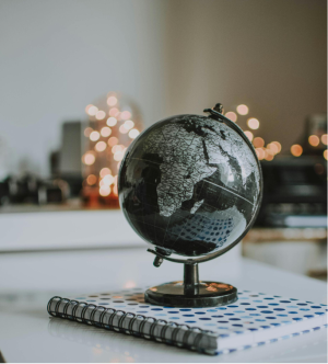 Globe on a notebook, symbolizing global priorities and initiatives for 2024, with blurred lights in the background reflecting adaptability and transformation.