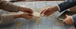 Hands meeting over a world map symbolizing global leadership and cross-cultural connections, representing Muralys' focus